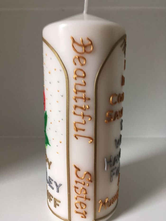Side of a candle reading Beautiful Sister in gold script