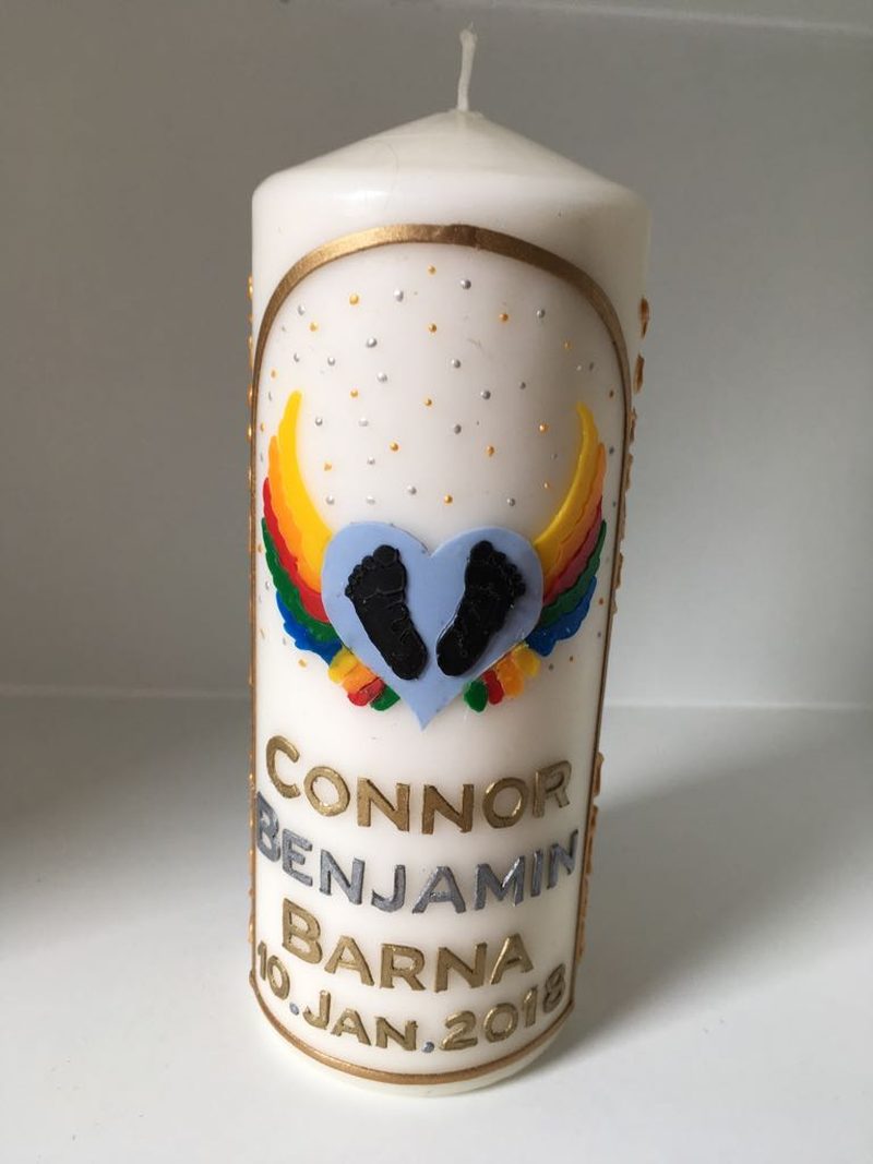 Candle for Connor Benjamin Barna with rainbow angel wings around two tiny footprints