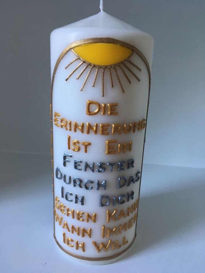Candle with a golden sun and a German inscription about memory
