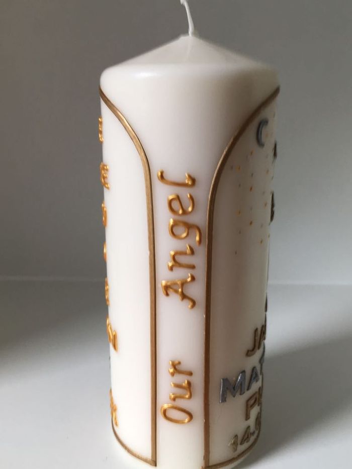 Side of a candle reading Our Angel in gold script